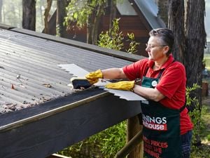 A Bunnings team member cleaning out the gutters.