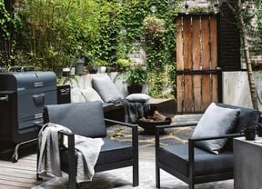 Outdoor lounge with two chairs and a BBQ next to it.