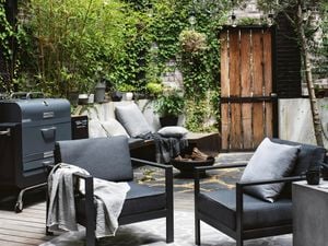 Outdoor lounge with two chairs and a BBQ next to it.