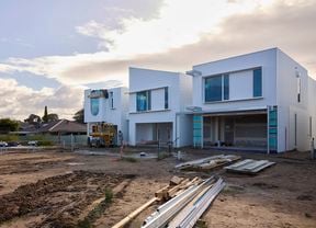 A half complete building on a clean jobsite with mud in the foreground.