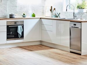 Grey themed U shaped kitchen against cream and white walls with two stools in front