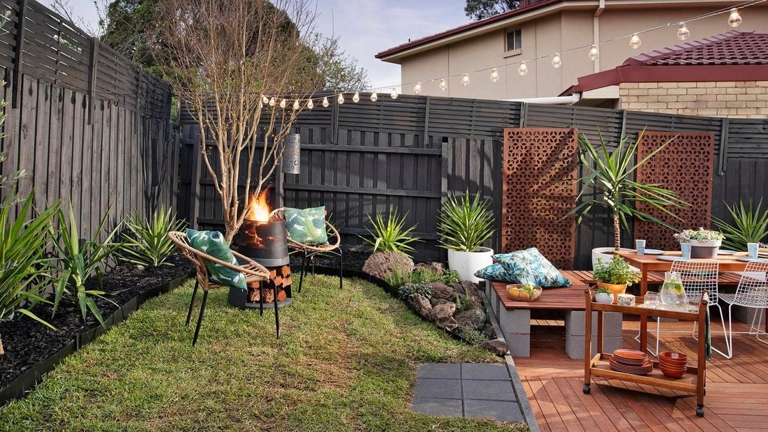 Renovated backyard outdoor area with fire pit, festoon lighting, decking and outdoor furniture.