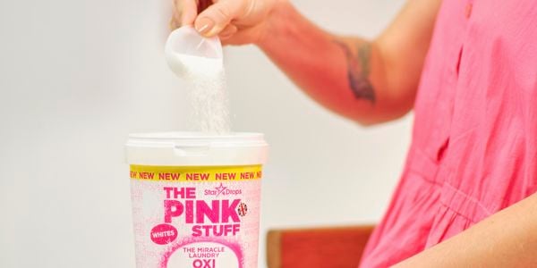 A woman scooping some Oxi Powder from a container.
