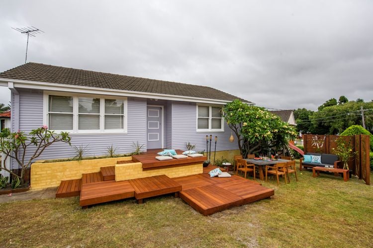 A vibrant brick and timber deck with throw pillows and a tree nearby