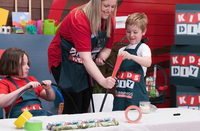 A boy is adding rice to a hula hoop with a paper funnel to make some funny sound. 
