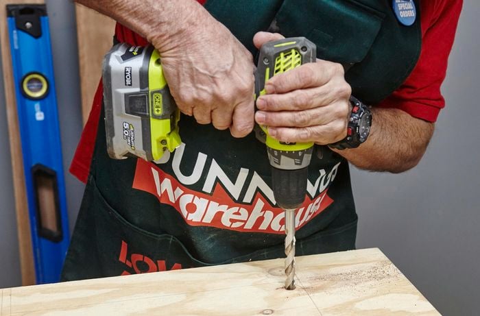 Person drilling hole in ply panel