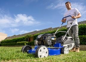 A person wearing ear and eye protection mowing grass with a Victa Power Mulcher