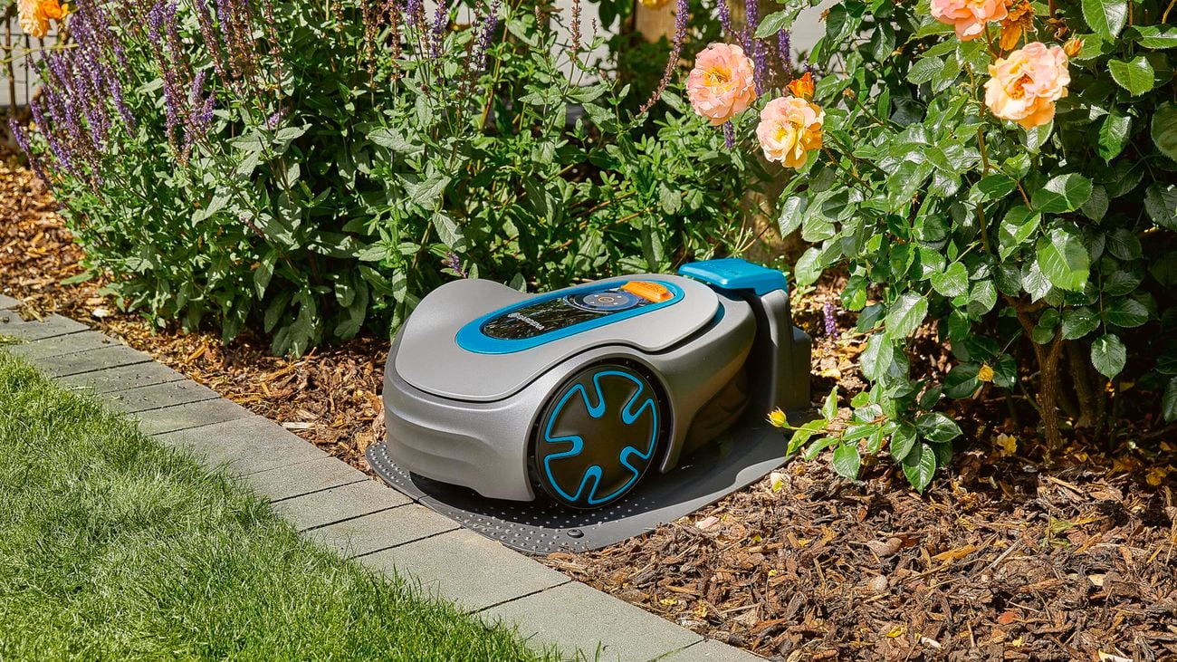 Gardena robotic lawnmower parked in a garden on its charging station