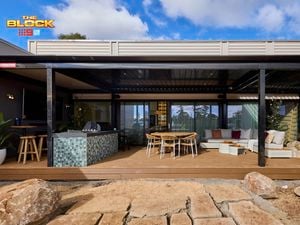 Back of a house with an outdoor setting, lounge and kitchen on decking.