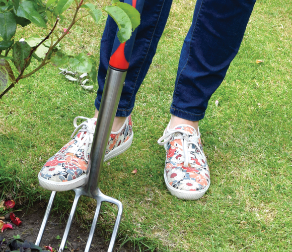 Close up of person digging a garden fork into a garden bed