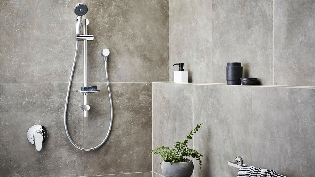 Chrome showerhead in focus in bathroom 