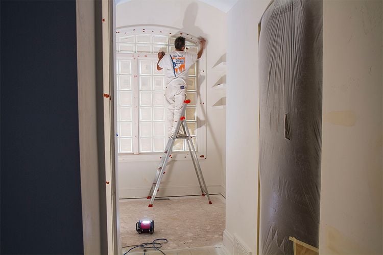 Painter standing on platform of ladder
