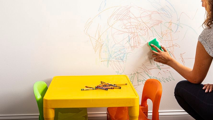 A person cleaning a wall with crayon marks with the Eraser Daddy.