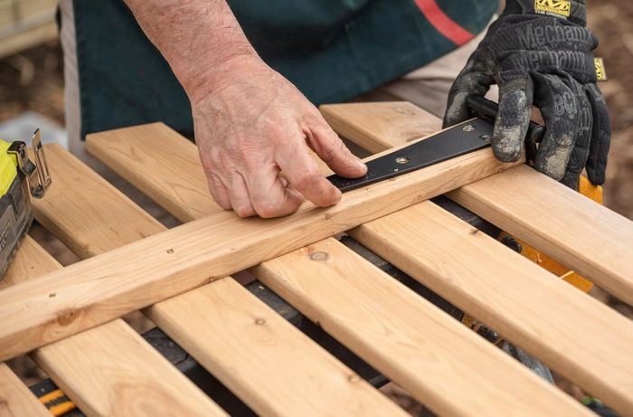 A Bunnings Team Member holding a hinge on a piece of timber