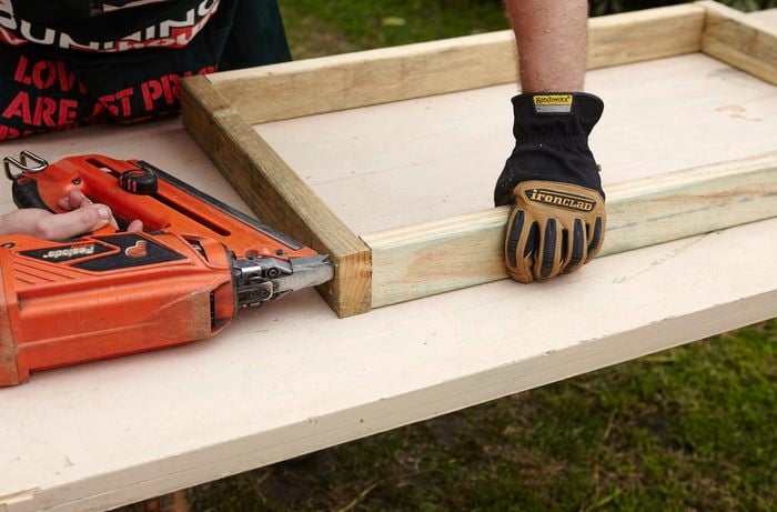 A wooden frame being assembled on a workbench by a Bunnings team member with a nail gun as part of a chicken coop