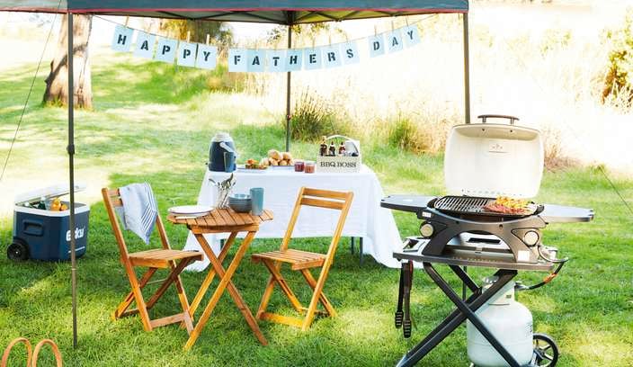 Outdoor picnic area with timber sun chairs, picnic table and happy fathers day banner