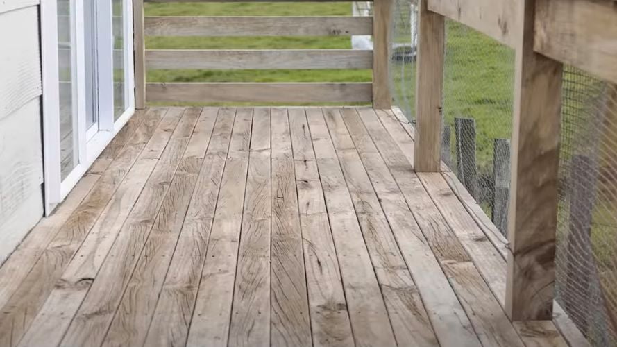 Deck and fencing made of light wood, with grass in the background.