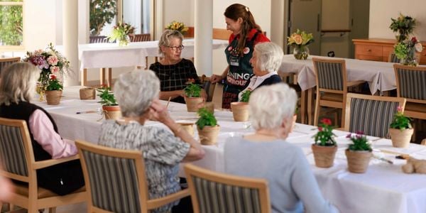 A Bunnings Team Member with ladies sitting at a table with pot plants on it.