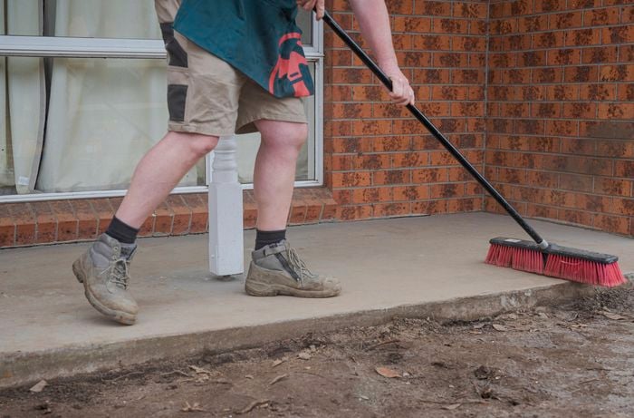 A person sweeping the concrete using a broom.