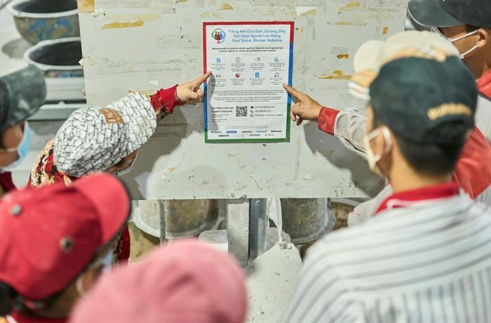 Factory workers looking at a safety poster 
