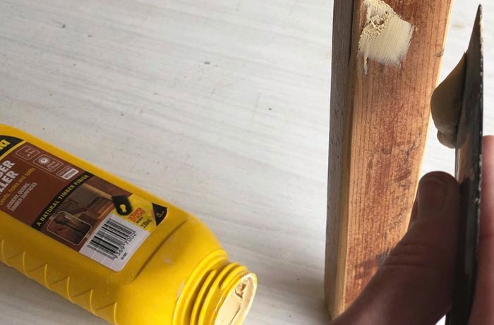 Person applying timber filler to a piece of timber