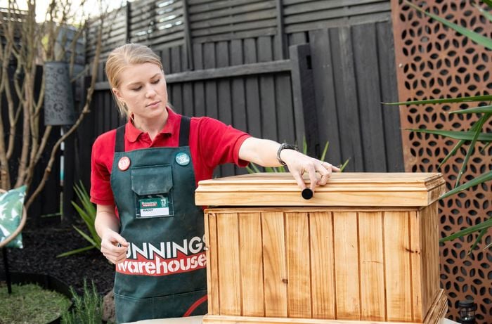 Woman positioning a knob on the lid of a wooden chest