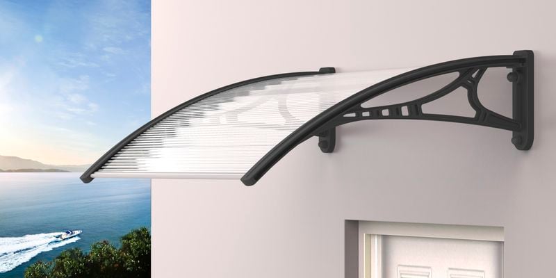 Metal framed window canopy above a door with a seascape in the background