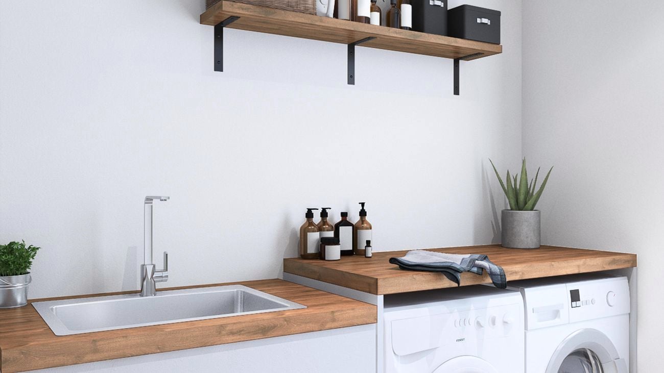 Laundy with timber benchtop, washing and drying machines, soaps, plants and cloth.