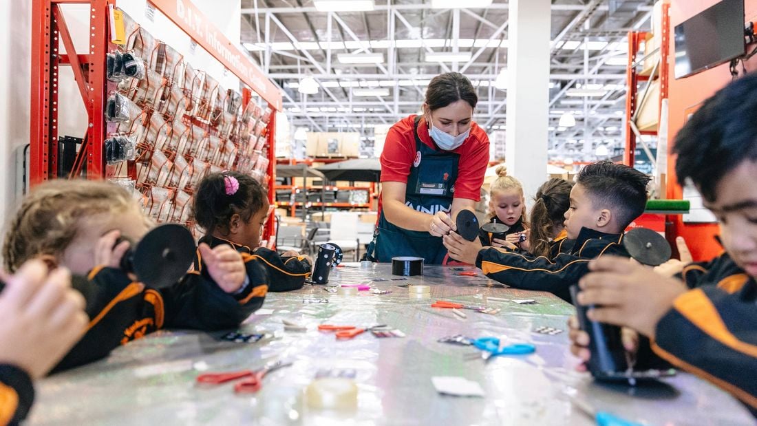 School children assembling Matariki kaleidoscopes with the help of a Bunnings team member