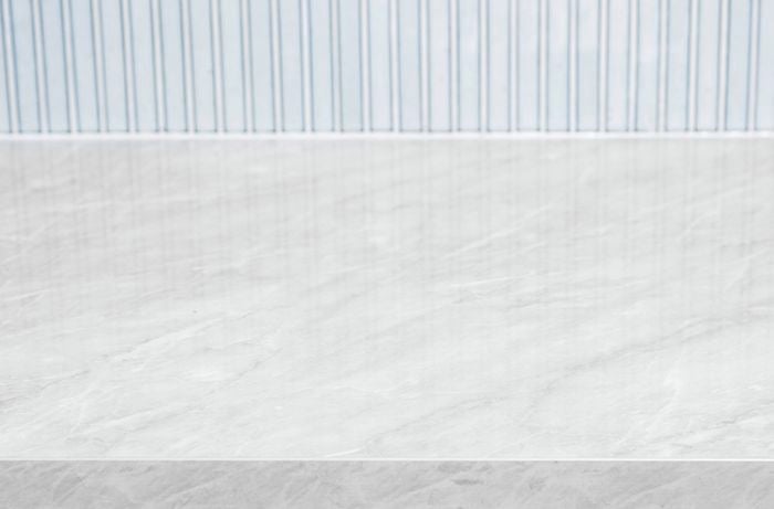 Grey marble benchtop with pale blue splashback behind it.