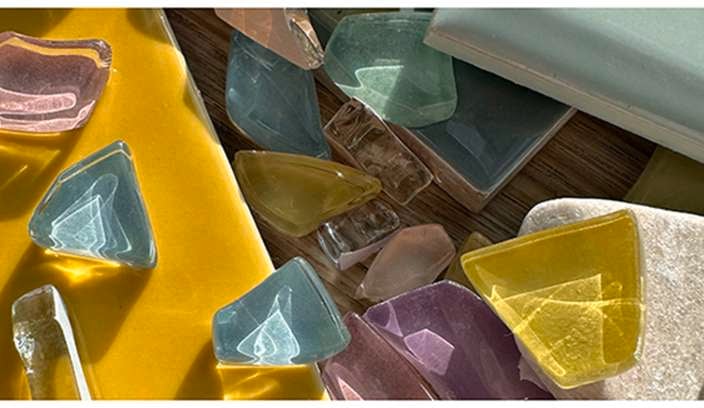 Pieces of different coloured glass on top of tiles and a stone.