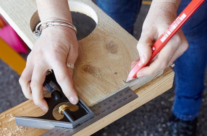 A person marking a length of timber using a measuring tape and pencil