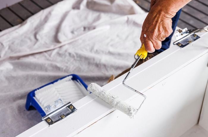A person painting the bench seat.