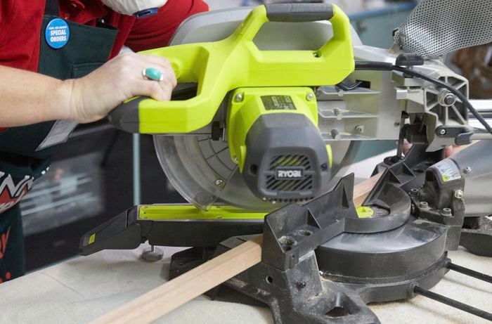 Person cutting length of timber with circular saw.