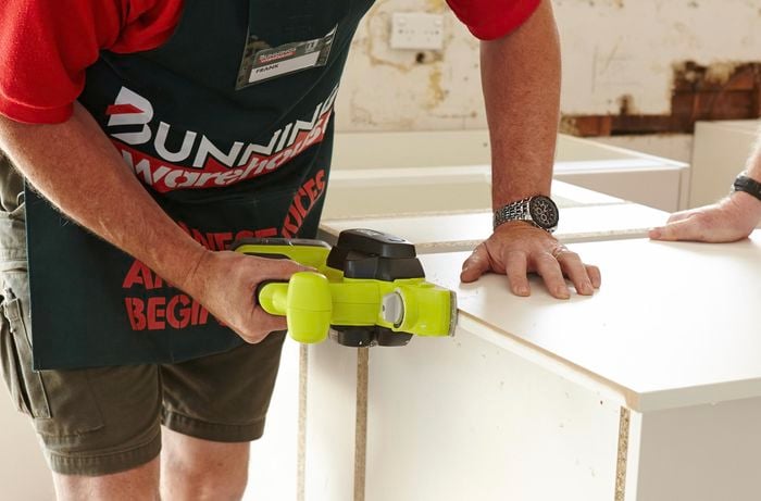 Person using a plane to trim the cabinet panel to size