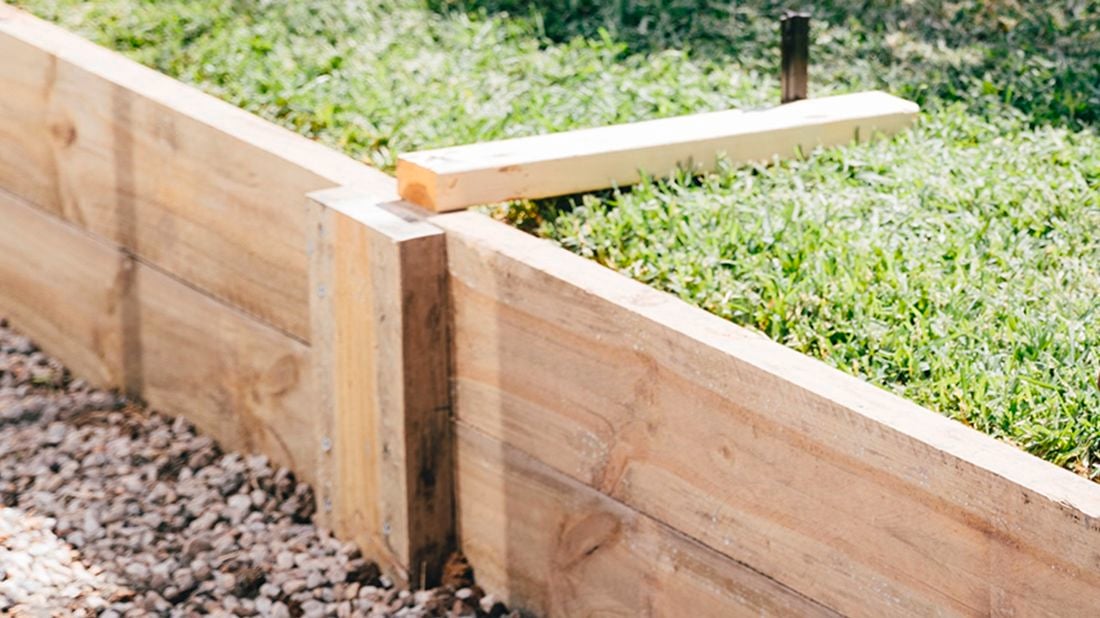 A timber retaining wall with a raised section of lawn