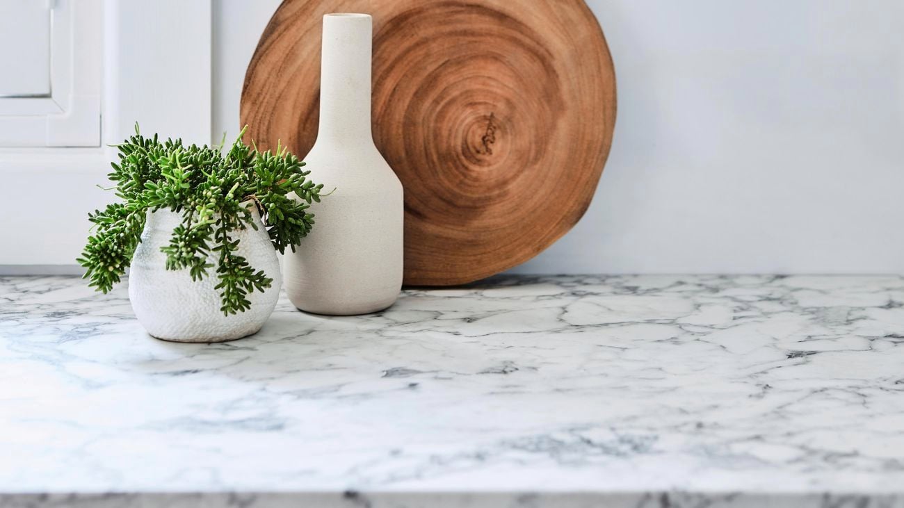 Marble benchtop with wooden chopping board and plants.