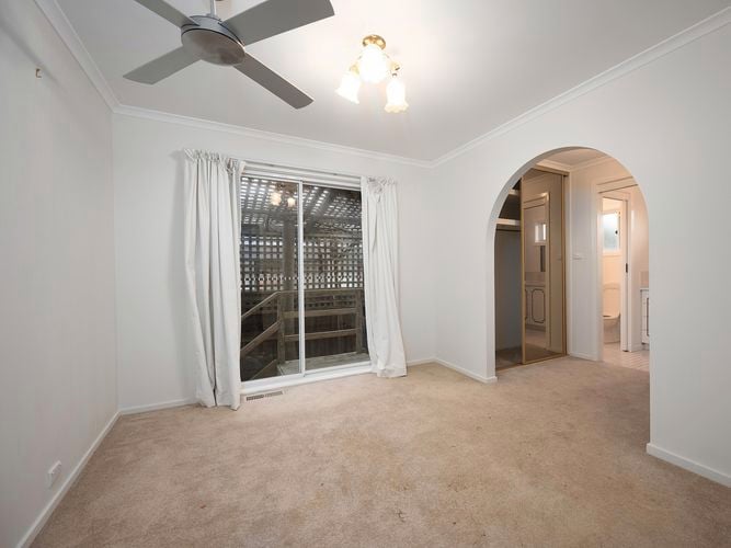 A room with carpet on the floor, ceiling fan, an archway and a glass sliding door to outside