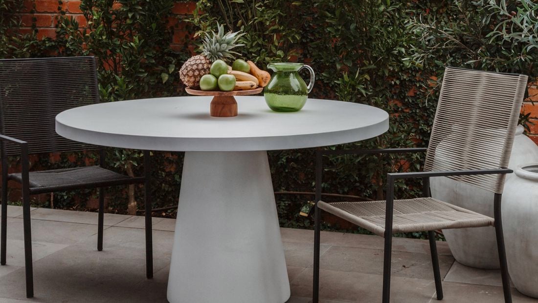 Outdoor furniture set outside, in front of plants and a brick wall