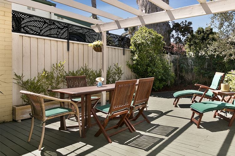 Backyard timber decking with timber dining table and lounge chairs