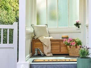 An entranceway featuring spring flowers and a timber daybed