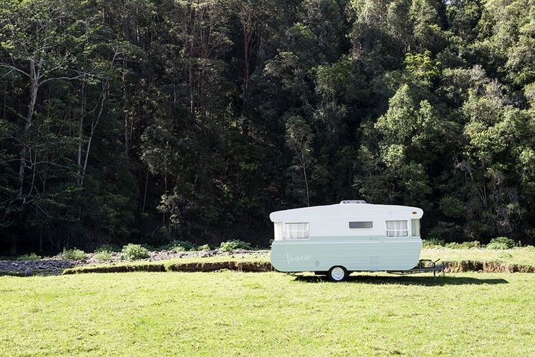 Longshot of a caravan parked in front of a forest