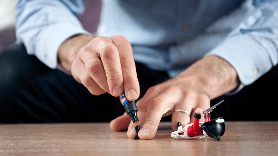 Man repairing broken toy figurine with Loctite All Plastics Glue.