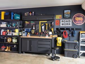 A garage with workbenches, storage cabinets, tools and old signs hanging on the walls.