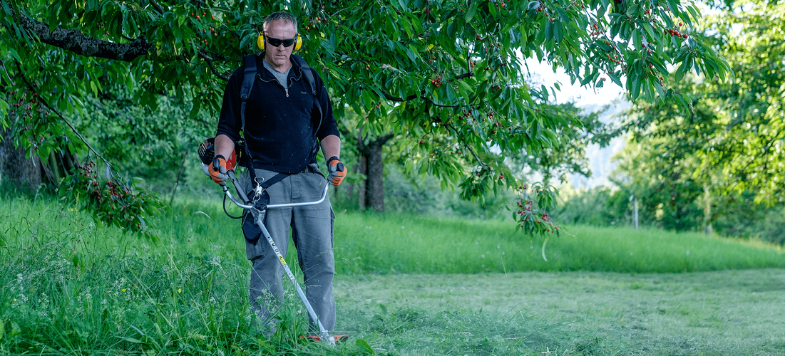 Man using whipper snipper to cut long grass