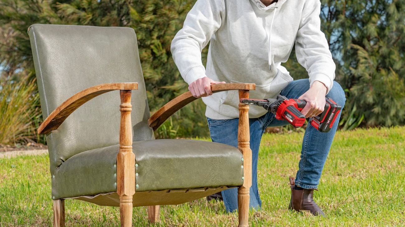 Person using a file sander on an armchair.