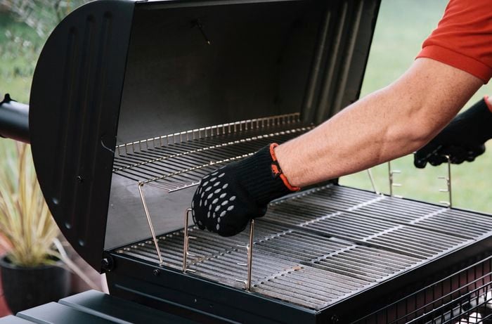 Person adjusting the height of the rack in a smoker