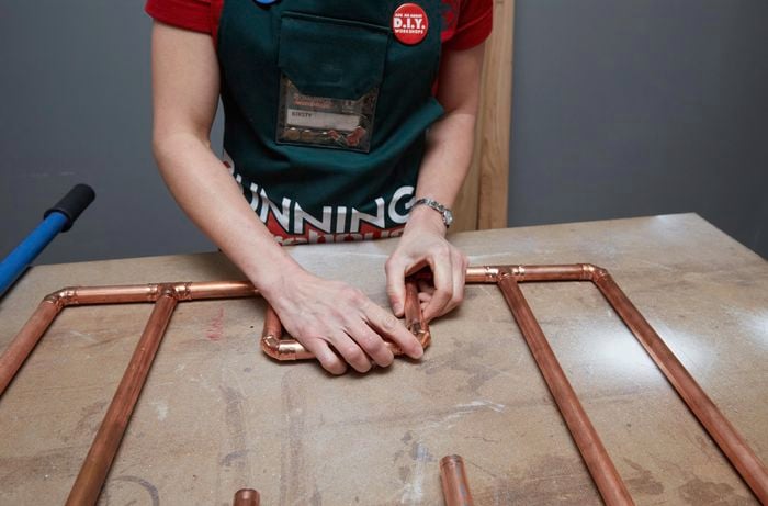 Person joining together two sides of a copper rack