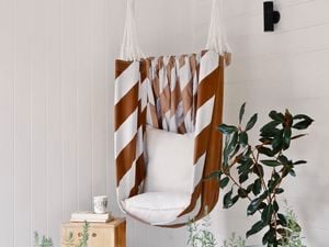 Brown and white striped hammock chair hanging in a white painted undercover area