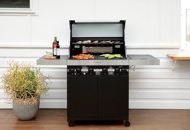 4-burner barbecue on deck with vegetables and meat cooking